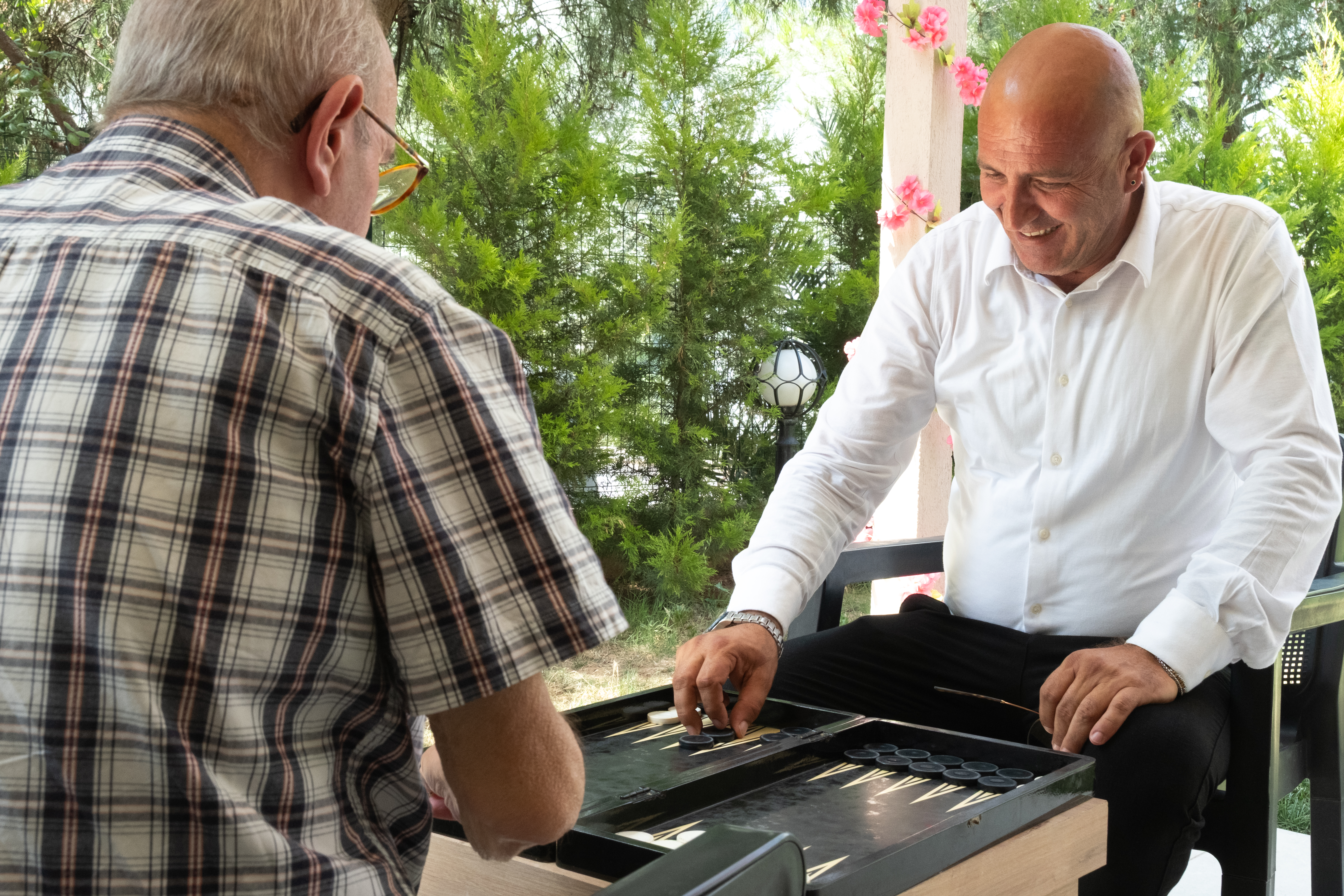 Bahçede tavla oynayan iki kişi